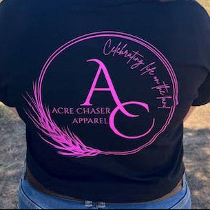 Person wearing a black SHIRT with pink logo in an outdoor setting